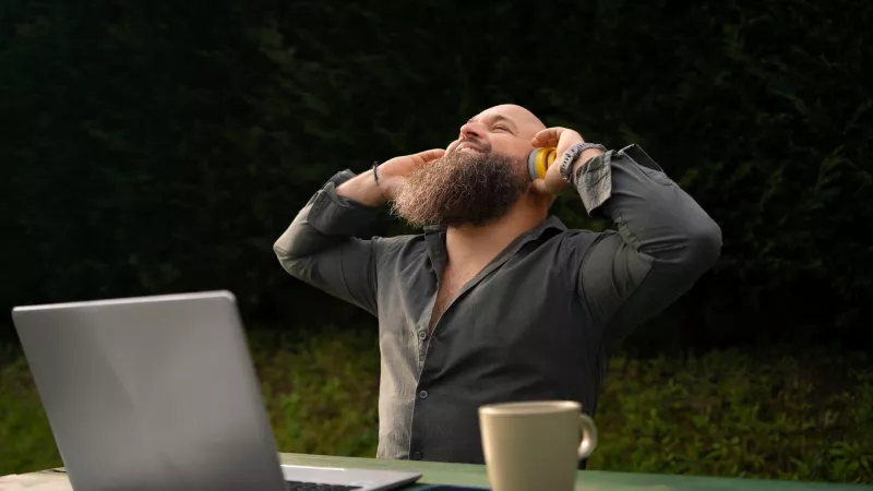 Image d'un homme heureu qui écoute de la musique tout en travaillant en extérieur.
