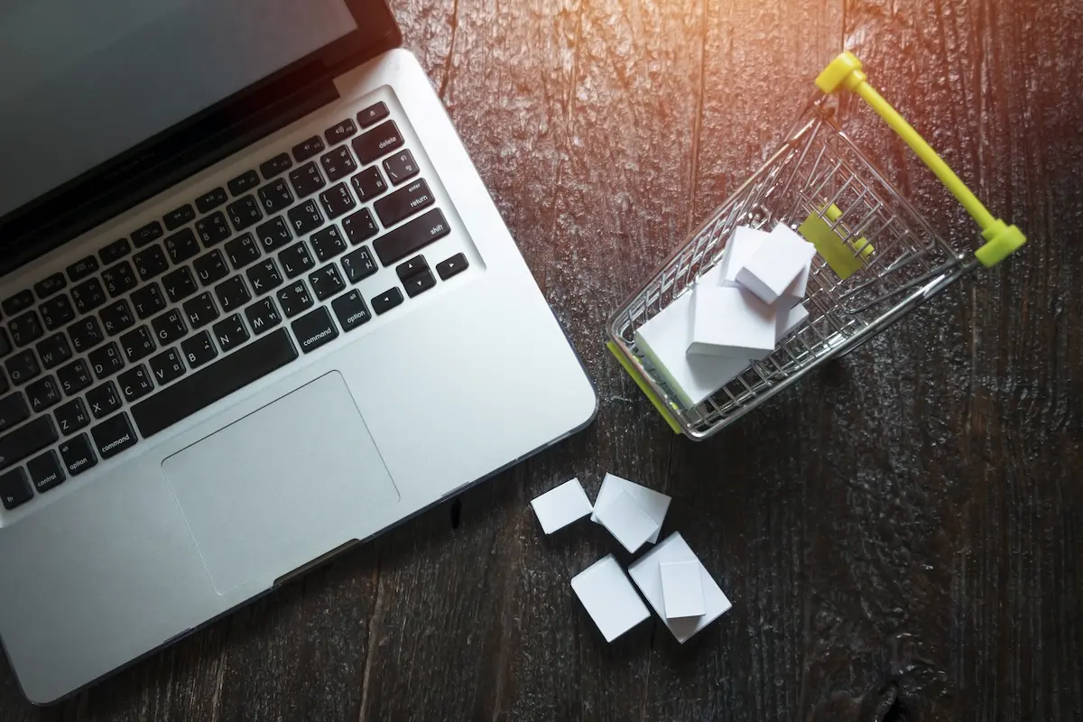 Un petit caddie de suppermarché à côté d'un ordinateur portable