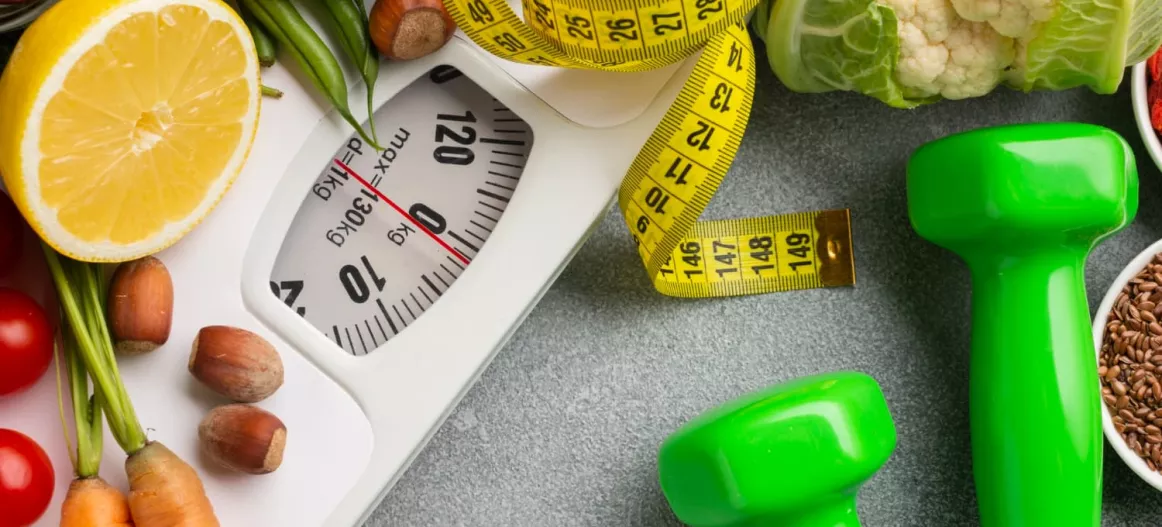 Photo d'illustration de l'article montrant une balance, un ruban mètre et des légumes symbolisant les régimes.